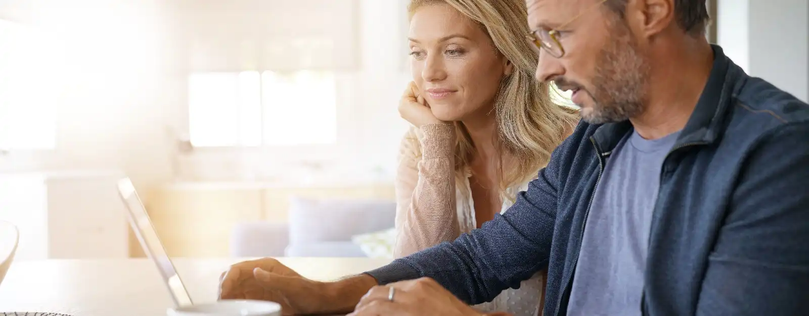Man and woman sitting in home looking at laptop